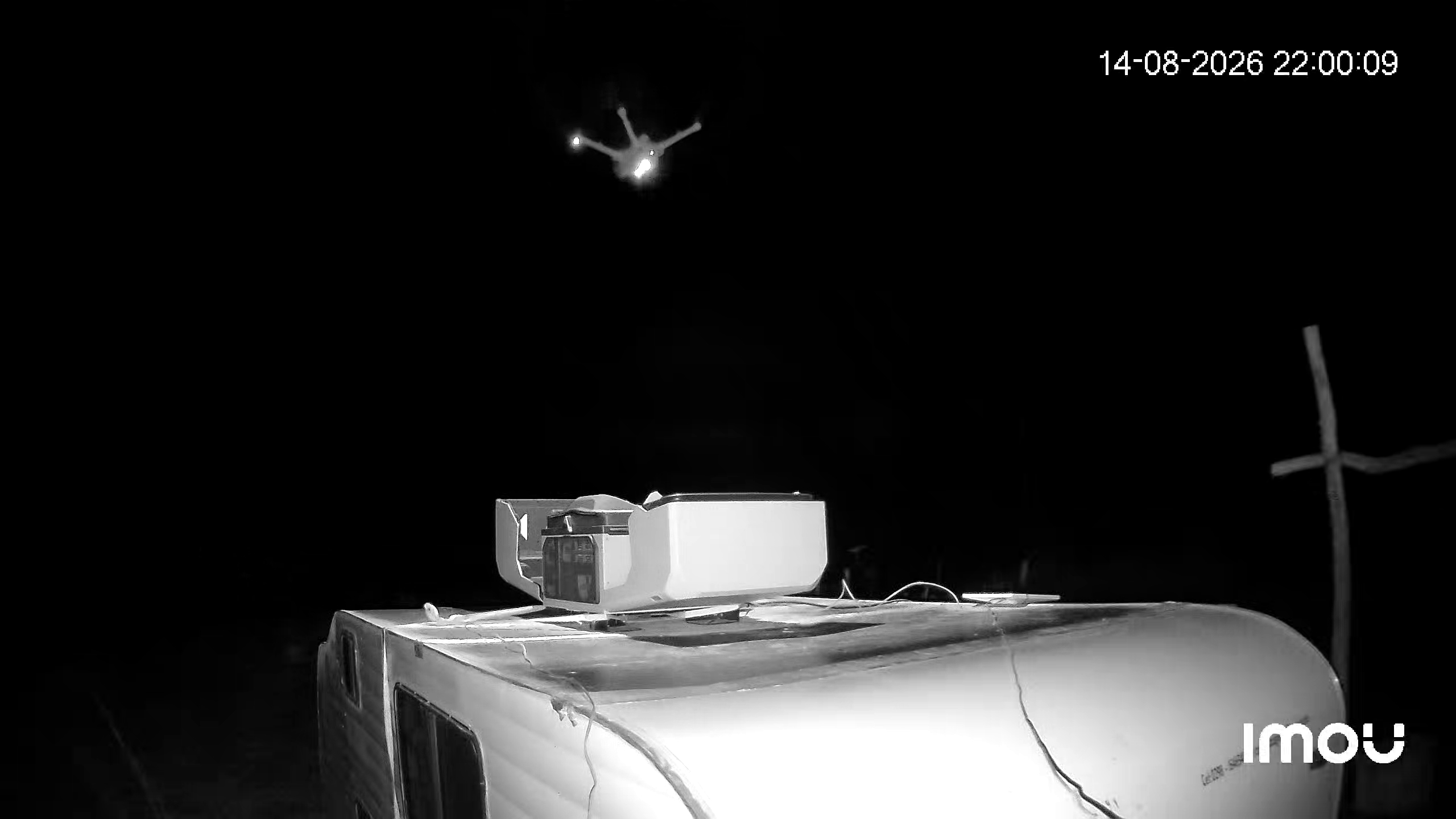 DJI Dock en operación nocturna. Drone en vuelo sobre la unidad móvil. 14 de agosto de 2026, 22:00.